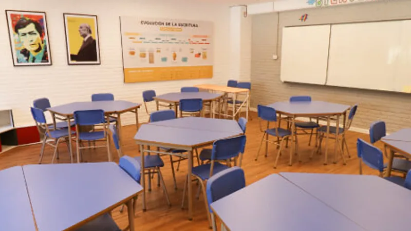 Aula del Colegio Chesterton con mesas modulares azules, pizarra blanca y letrero de Bienvenidos.