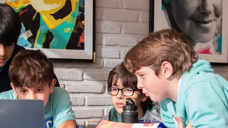 Cuatro alumnos del Colegio Chesterton reunidos frente a una computadora portátil con un proyecto de robótica.